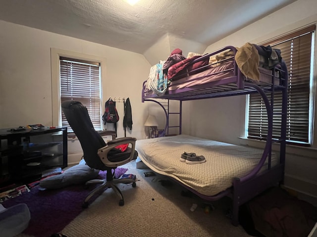 bedroom with carpet, a textured ceiling, and vaulted ceiling