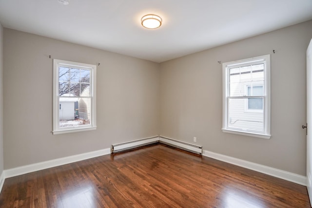 spare room featuring dark hardwood / wood-style flooring, plenty of natural light, and a baseboard heating unit