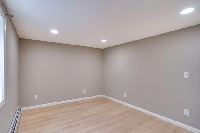 spare room with baseboard heating and light hardwood / wood-style flooring