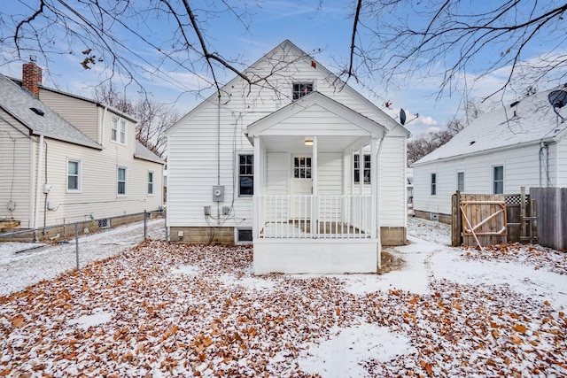 snow covered back of property featuring a porch