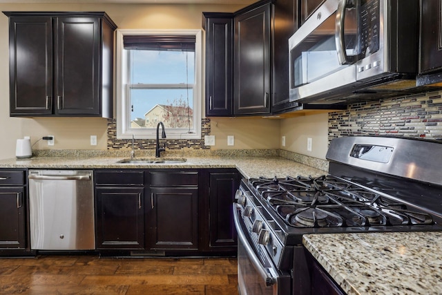 kitchen featuring sink, appliances with stainless steel finishes, dark hardwood / wood-style flooring, light stone counters, and dark brown cabinetry