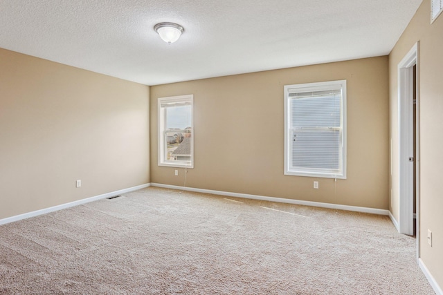 carpeted empty room featuring a textured ceiling