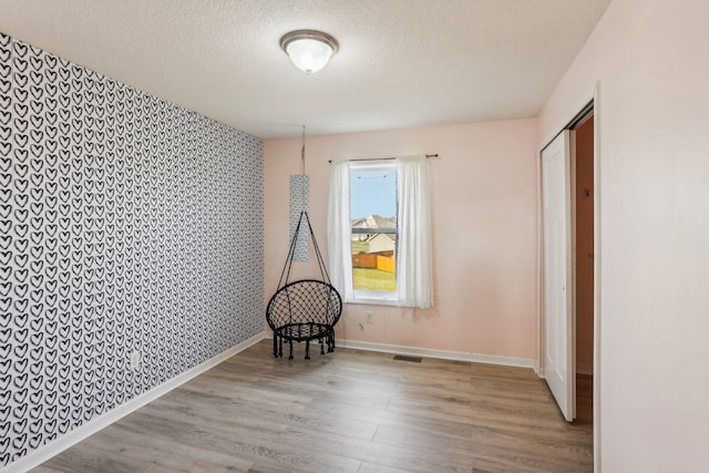 unfurnished room featuring light hardwood / wood-style floors and a textured ceiling