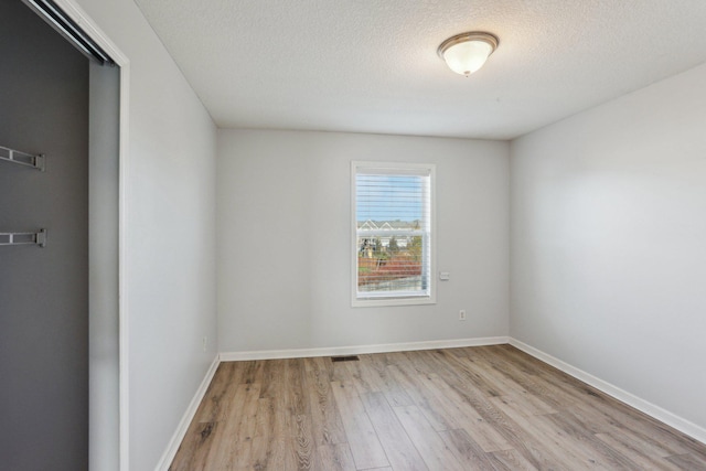 spare room with light hardwood / wood-style floors and a textured ceiling