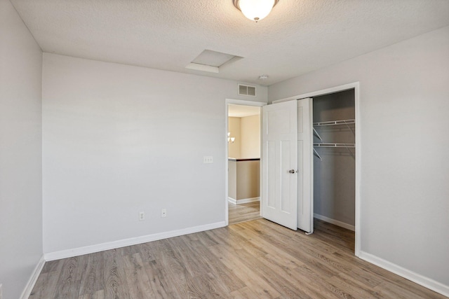 unfurnished bedroom with a textured ceiling, light wood-type flooring, and a closet