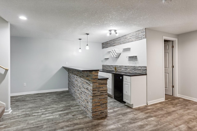 bar featuring dark hardwood / wood-style flooring, white cabinets, pendant lighting, and a textured ceiling