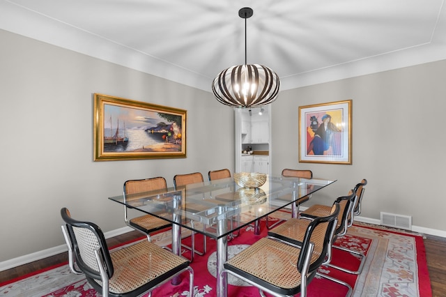 dining area with an inviting chandelier, baseboards, wood finished floors, and visible vents