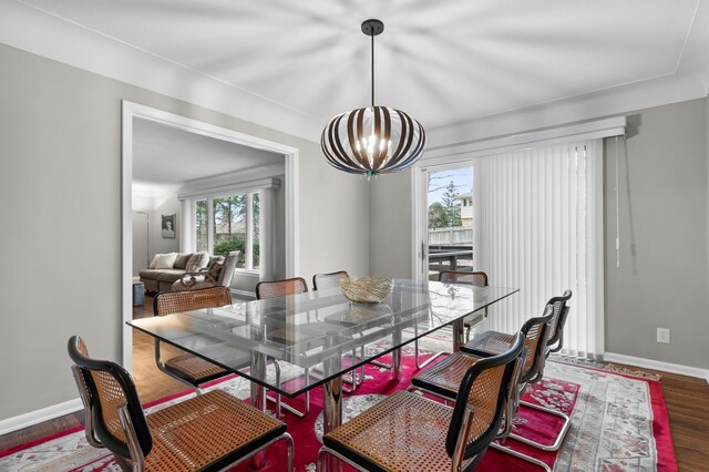 dining area featuring baseboards, wood finished floors, and a notable chandelier