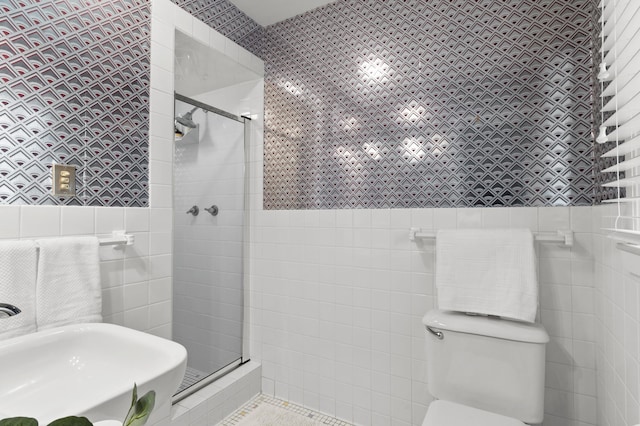 full bathroom featuring tile walls, a stall shower, a sink, tile patterned floors, and toilet