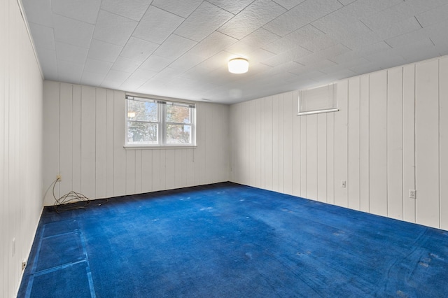 carpeted spare room with wood walls