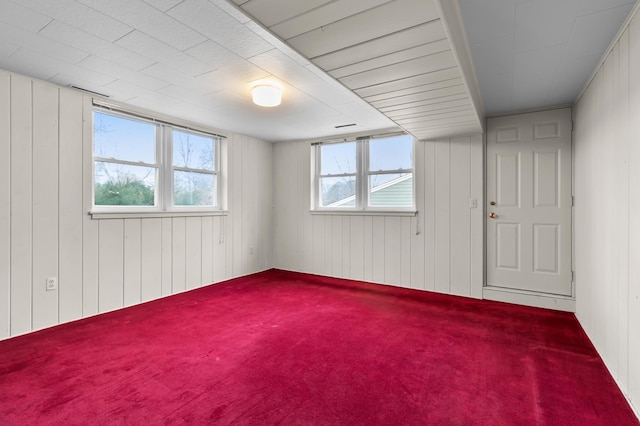 carpeted spare room with wooden walls