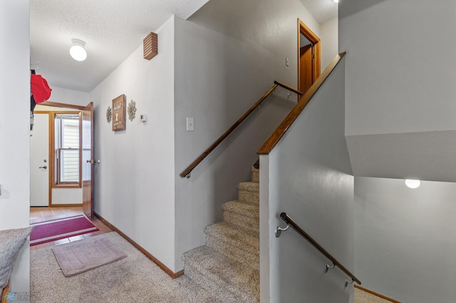 stairs featuring lofted ceiling, a textured ceiling, and carpet flooring