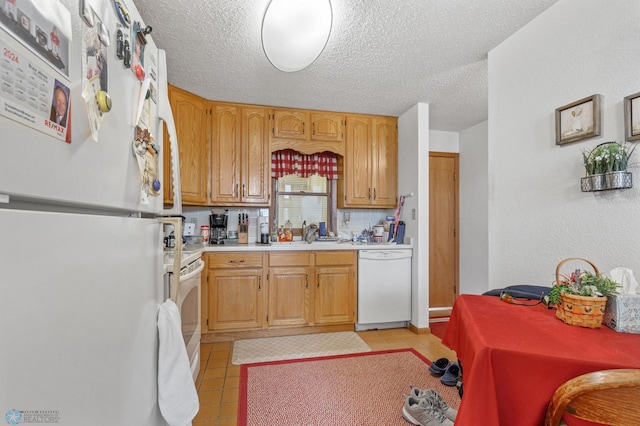 kitchen with white appliances, a textured ceiling, sink, and light tile patterned flooring