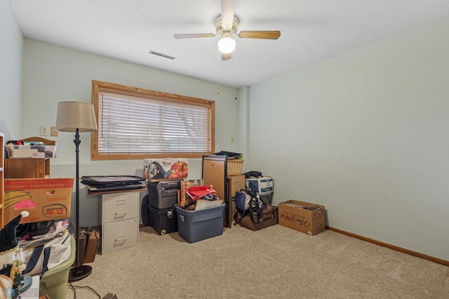 home office with a textured ceiling, ceiling fan, and carpet floors