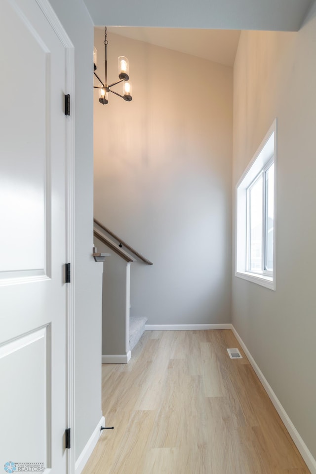 stairway with hardwood / wood-style flooring and an inviting chandelier