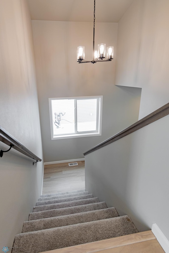 stairway with a chandelier and hardwood / wood-style flooring