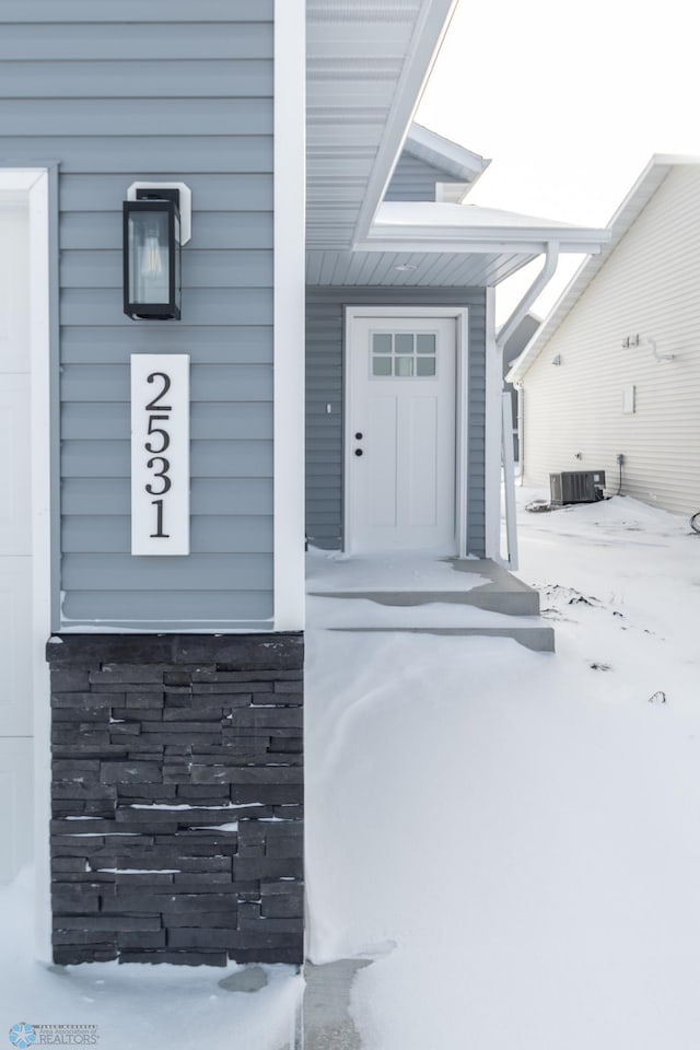 snow covered property entrance with central AC