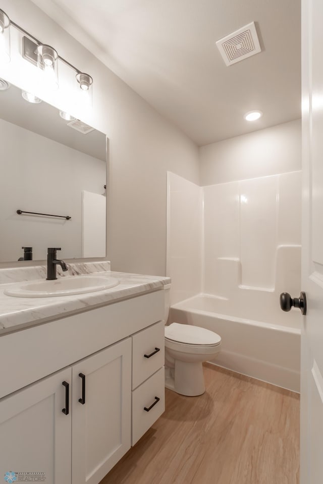 full bathroom with vanity, hardwood / wood-style floors, shower / bathing tub combination, and toilet