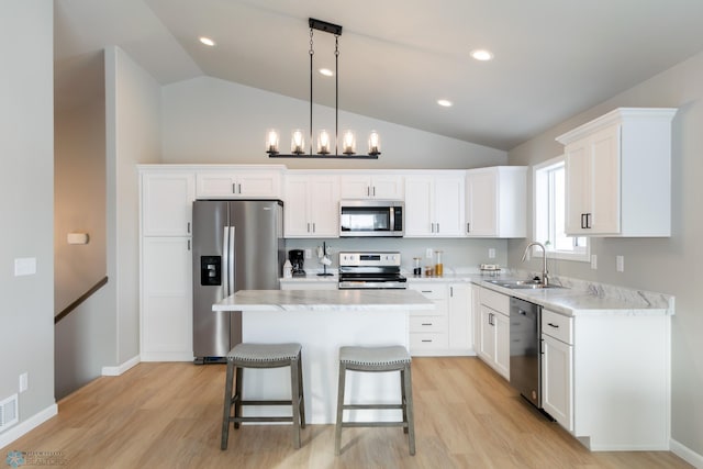 kitchen featuring appliances with stainless steel finishes, sink, decorative light fixtures, white cabinets, and a kitchen island