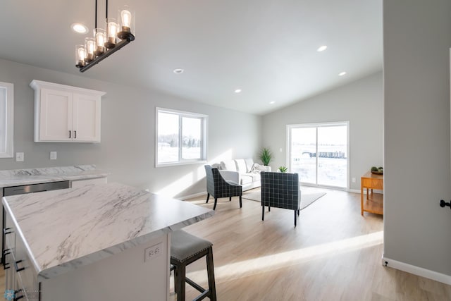 kitchen with vaulted ceiling, white cabinetry, plenty of natural light, and decorative light fixtures