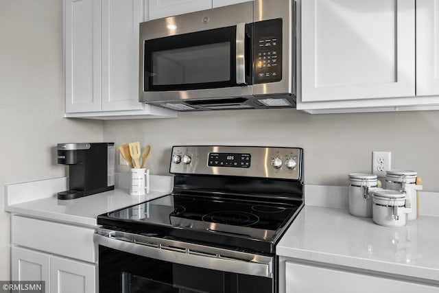 kitchen with appliances with stainless steel finishes, white cabinetry, and light stone countertops