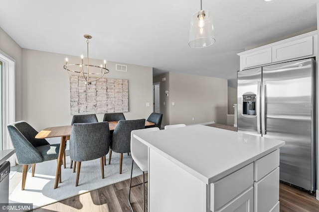 kitchen with appliances with stainless steel finishes, a center island, pendant lighting, white cabinets, and dark wood-type flooring