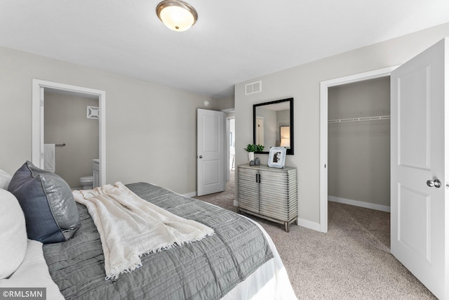 bedroom with a closet, ensuite bath, an AC wall unit, and carpet