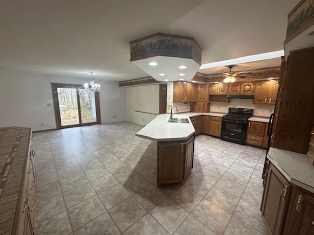 kitchen featuring sink, a kitchen island, ceiling fan with notable chandelier, lofted ceiling, and black gas range oven