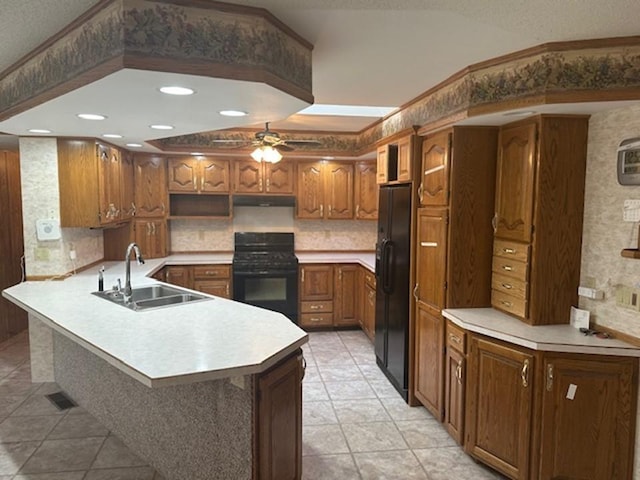 kitchen with black appliances, sink, kitchen peninsula, ceiling fan, and light tile patterned floors