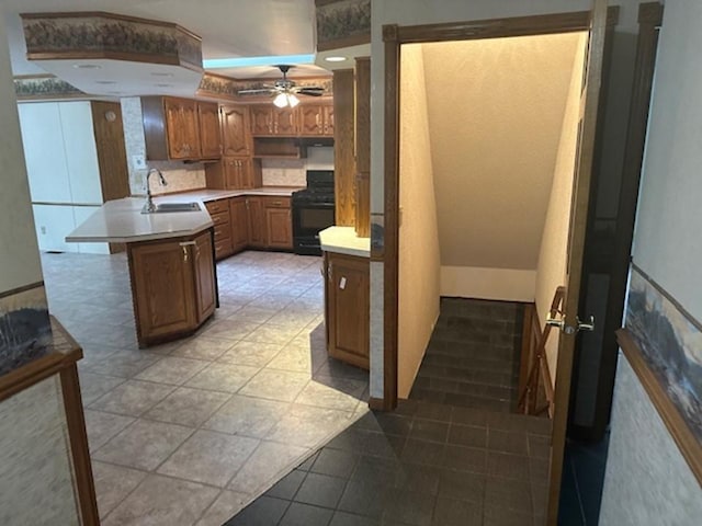 kitchen with black range, sink, a kitchen island, ceiling fan, and light tile patterned floors