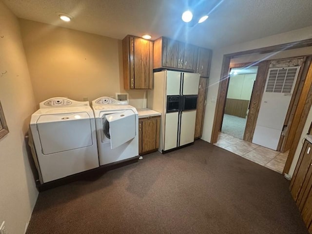 clothes washing area featuring light carpet, a textured ceiling, separate washer and dryer, and cabinets