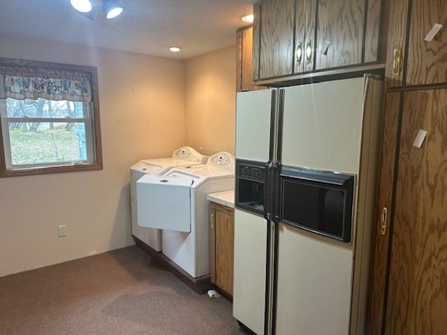 washroom featuring a textured ceiling, washing machine and dryer, cabinets, and dark carpet