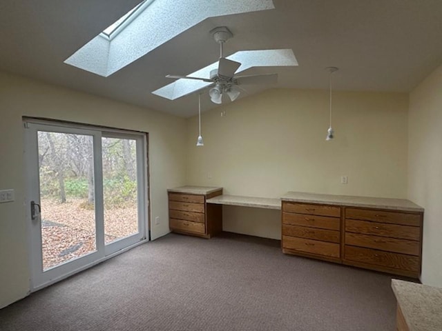 unfurnished bedroom with access to outside, built in desk, ceiling fan, lofted ceiling with skylight, and light colored carpet