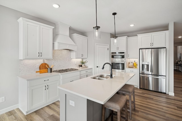 kitchen with stainless steel appliances, hardwood / wood-style floors, sink, white cabinetry, and premium range hood