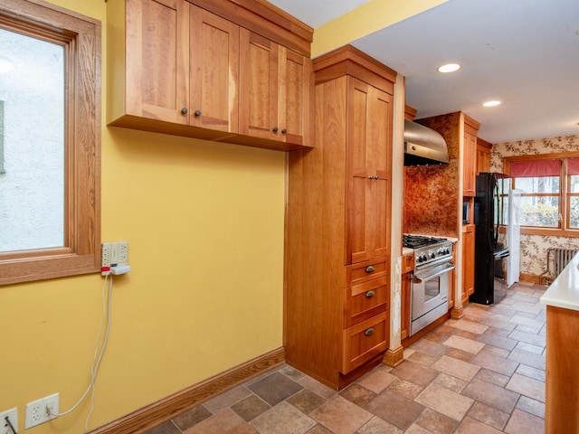 kitchen featuring tasteful backsplash, range hood, black refrigerator, and high end stainless steel range