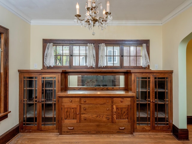 bar with light hardwood / wood-style floors, an inviting chandelier, and ornamental molding