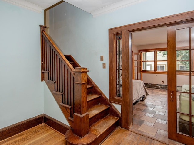 staircase with french doors, crown molding, and hardwood / wood-style flooring