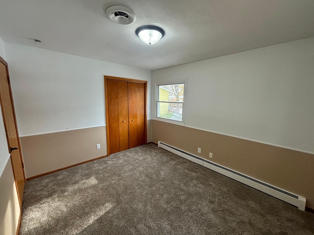 unfurnished bedroom featuring a closet, carpet, a textured ceiling, and baseboard heating