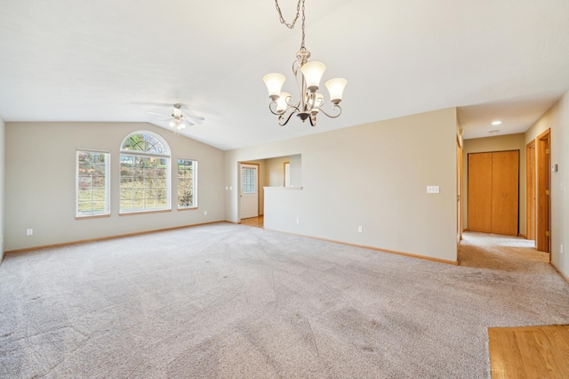 empty room with light colored carpet, lofted ceiling, and ceiling fan with notable chandelier