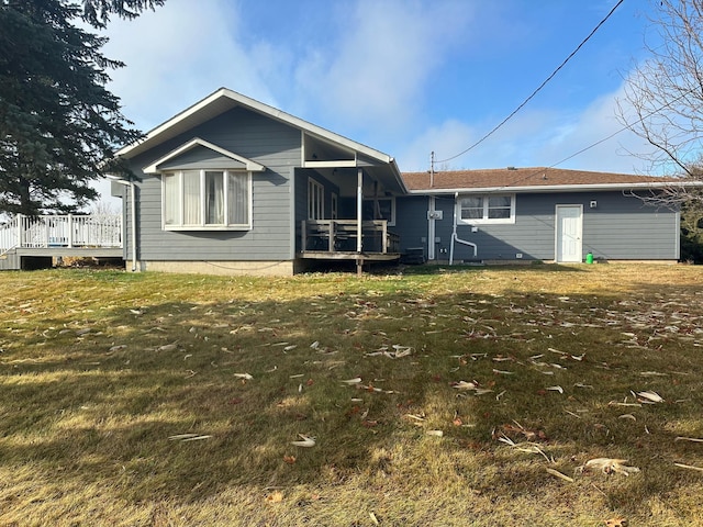 rear view of property featuring a lawn and a deck