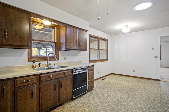 kitchen with black dishwasher, dark brown cabinets, and sink