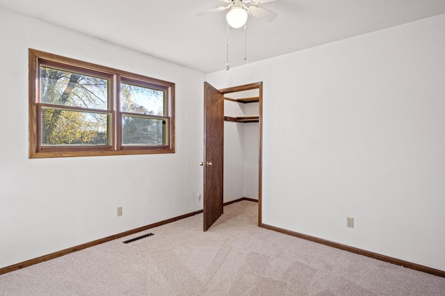 unfurnished bedroom with a closet, light colored carpet, and ceiling fan