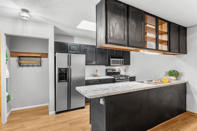 kitchen with tasteful backsplash, sink, light hardwood / wood-style floors, and stainless steel appliances