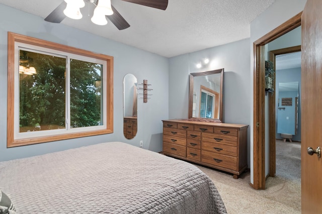 carpeted bedroom featuring a textured ceiling and ceiling fan