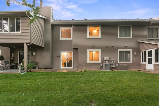 rear view of property with a yard, a patio, and central AC