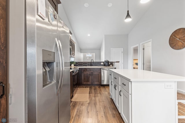 kitchen featuring wood-type flooring, sink, appliances with stainless steel finishes, a kitchen island, and decorative light fixtures