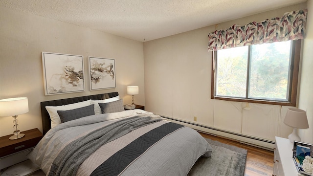 bedroom with baseboard heating, wood finished floors, and a textured ceiling