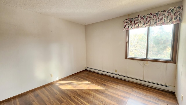 empty room with baseboard heating, wood finished floors, and a textured ceiling
