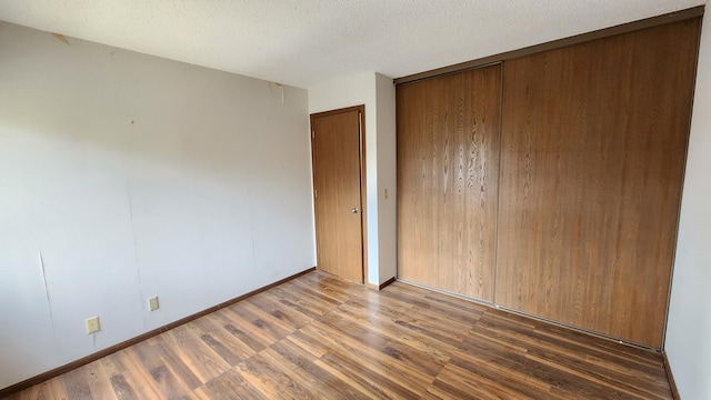 spare room with baseboards, wood finished floors, and a textured ceiling