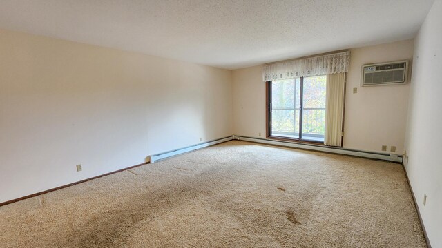 empty room featuring a wall mounted AC, a textured ceiling, carpet flooring, and baseboards